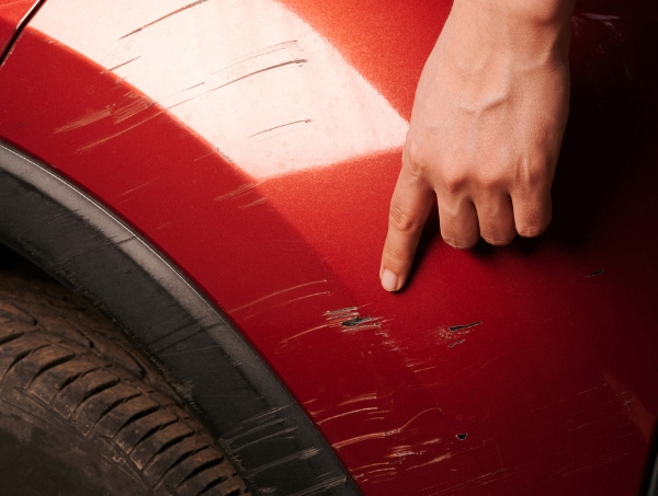 Car scratch on a red panel being assessed for SMART repair in Ayr